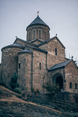 Fototapeta na wymiar Ancient stone monastery in Georgia. Ancient church of dark stone on the hill. Old architecture, historical heritage