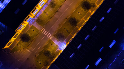 Aerial perpendicular night view of an interior alley of a building overlooked by windows and balconies