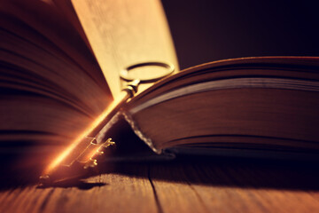image of open antique book on wooden table with vintage key