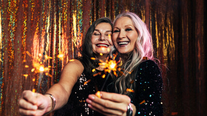 Two senior girlfriends having fun together holding sparklers