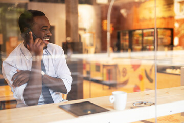 Businessman drinking coffee in cafe. Handsome African man talking to the phone while enjoying in fresh coffee