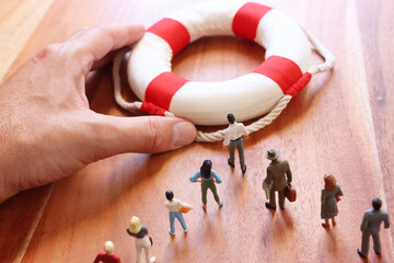 Concept image of life buoy protecting group of people. Rescue and support in times of crisis metaphor - obrazy, fototapety, plakaty