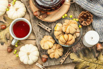Obraz na płótnie Canvas Autumn tea concept. Cookies with pumpkin puree, black tea in a glass teapot, fall decor