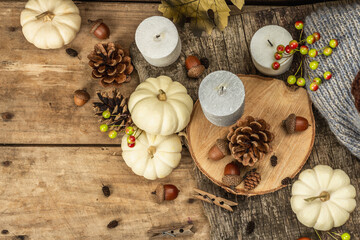 Autumn composition with traditional decor. White pumpkins, candles, fall leaves, acorns, cones