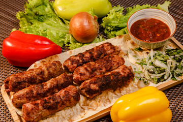 Closeup of kebab made with armenian receipt on table with peppers, greens and sauce