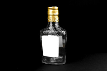 Mockup label on empty glass bottle of whiskey, cognac or vodka on a black background. Template,...