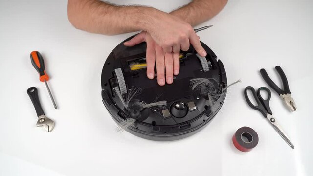 Worker Fixes Wheels of Vacuum Cleaner Robot