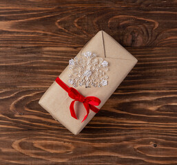 Christmas gift in craft paper on a wooden background.