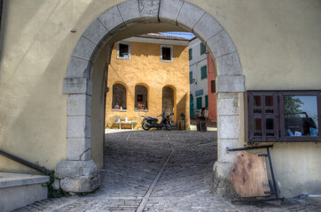 Istria, Croatia, April - View through an archway of a scooter parked in front of an old yellow house in the ancient town of Oprtalj