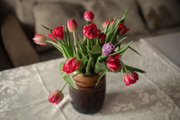 Spring flowers in vase on table. Beautiful spring tulips in vase on table against light background.