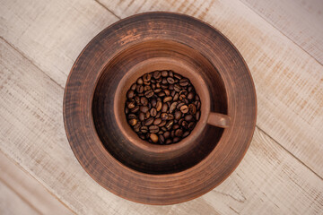 Coffee cup full of coffee beans. Brown coffee beans in earthenware.