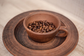 Coffee cup full of coffee beans. Brown coffee beans in earthenware.