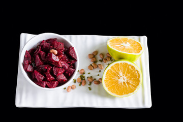 Sauteed Beetroot vegetable cooked in spices like bay leaf,star anise,garnished with butter,peanuts,green lentil,mint and sweet lime juice.Top view,selective focus on vegan curry ,on black background.