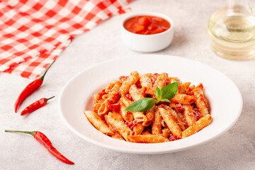 Classic italian pasta penne alla arrabiata with fresh basil on a light background