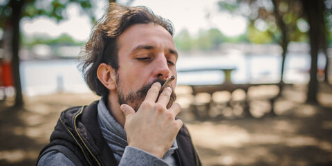 Closeup detail view of man smoke marijuana ganja joint cigarette