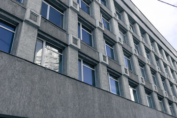 Windows of an old gray building. Bottom view of an office building with windows