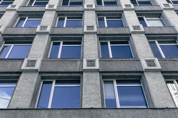 Gray wall with many windows. A background of a bottom view of a building with many windows
