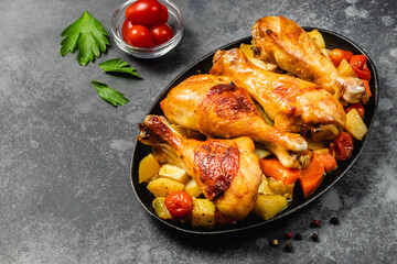 Ginger orange roast chicken with vegetables in cast iron skillet on dark background. Copy space.