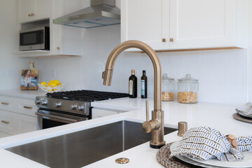 Modern kitchen detail of large curved brass faucet over deep sink.