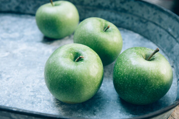 Ripe green apples in a large iron tray on a light background. Top view. Close up