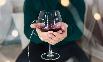 glass of red wine in hands of man and bokeh from Christmas lights. wine tasting. people, alcohol and drinks