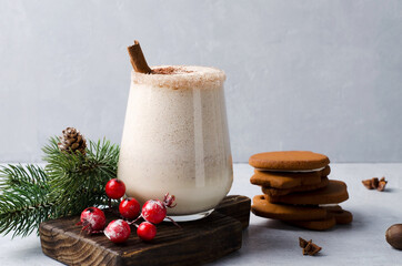 Milk-egg drink with thick foam, cinnamon and gingerbread on a light background, selective focus