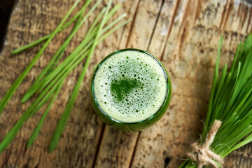 A glass of young barley grass juice with freshly grown barley grass