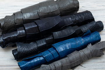 Colorful rolls of alligator leather. Grey black blue palette.
