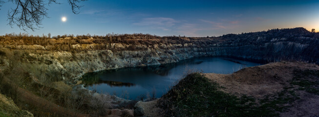 Flooded granite quarry at night. Panorama. Industrial landscape. Kryvyi Rih, Ukraine.