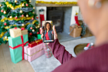 Woman making smartphone christmas video call with smiling african american woman