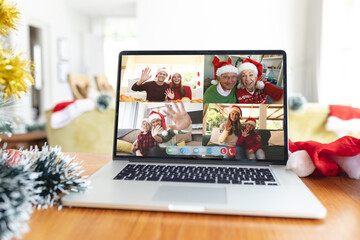 Happy caucasian family members waving on laptop group video call screen at christmas time