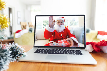 Happy senior caucasian man in santa costume waving on laptop video call screen at christmas time - Powered by Adobe