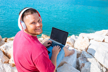 man freelancer working on laptop at city harbor bench