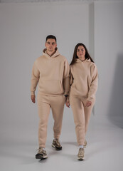 Couple posing in studio wearing beige hoodie