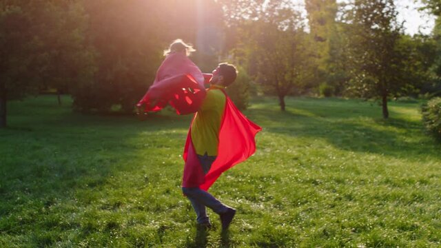 Happy time spend together father and son wearing superhero s suit they enjoy the time in the middle of the park dad take his son in arms and twist him. Shot on ARRI Alexa Mini.