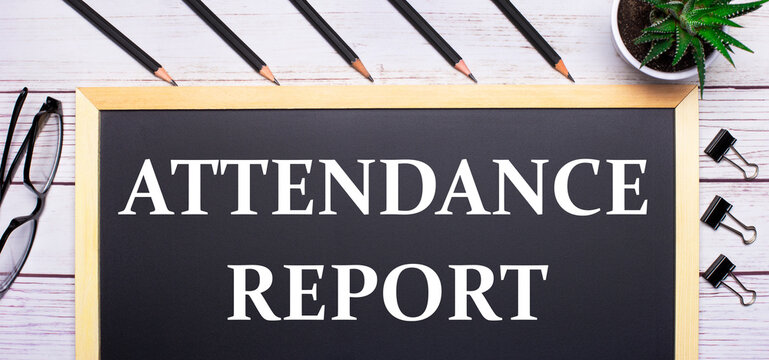On a light wooden table - a board with the text ATTENDANCE REPORT, pencils, plants, glasses and paper clips. Business concept