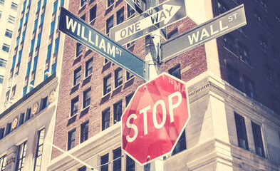 Wall Street, William Street, One Way and Stop road signs in downtown New York, color toning applied, USA.
