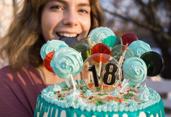 beautiful cake with numbers 18, lollipops and marshmallows on sticks and a happy joyful face of the...