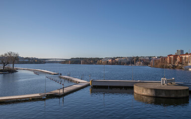 Fototapeta na wymiar An empty marina with jetty and a concrete safety bollard in the bay between the districts Kungsholmen and Bromma. A sunny color full autumn day in Stockholm