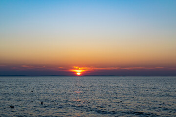 the setting sun against the backdrop of a calm sea