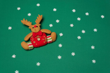 Christmas reindeer with red bow on green background with snow crystals