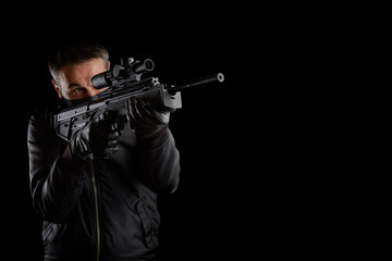 A man in dark clothes holds an automatic carbine in his hands. The face is covered with a mask,...