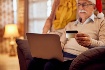 Close-up of mature couple shopping online for Christmas at home.