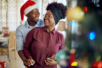 Cheerful African American couple has fun together on Christmas day at home.