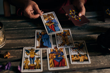 Close-up of a fortune teller displaying some tarot cards on a wooden table