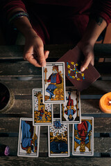 Close-up of a fortune teller displaying some tarot cards on a wooden table - obrazy, fototapety, plakaty