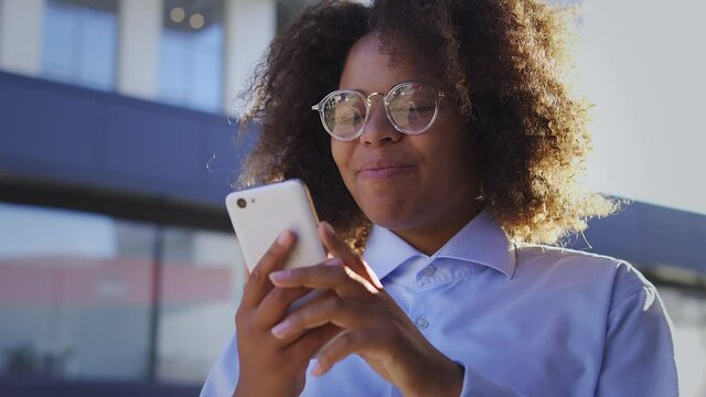 Extremely positive happy black woman with afro-hair making yes gesture reading good news on smartphone, entering university, successfully completing exams and receiving scholarship or grant, success