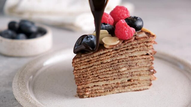Chocolate crepe cake with chocolate sauce and fresh berries. Layered cake