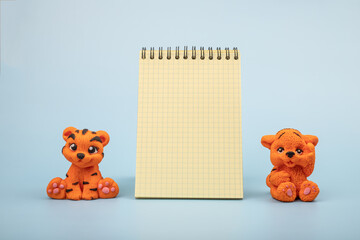 An orange tiger figurine on a blue background. The year 2022 is the year of the tiger according to...