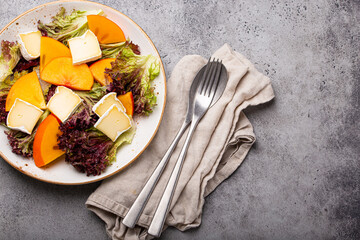 Healthy vegetarian persimmon salad with brie copy space
